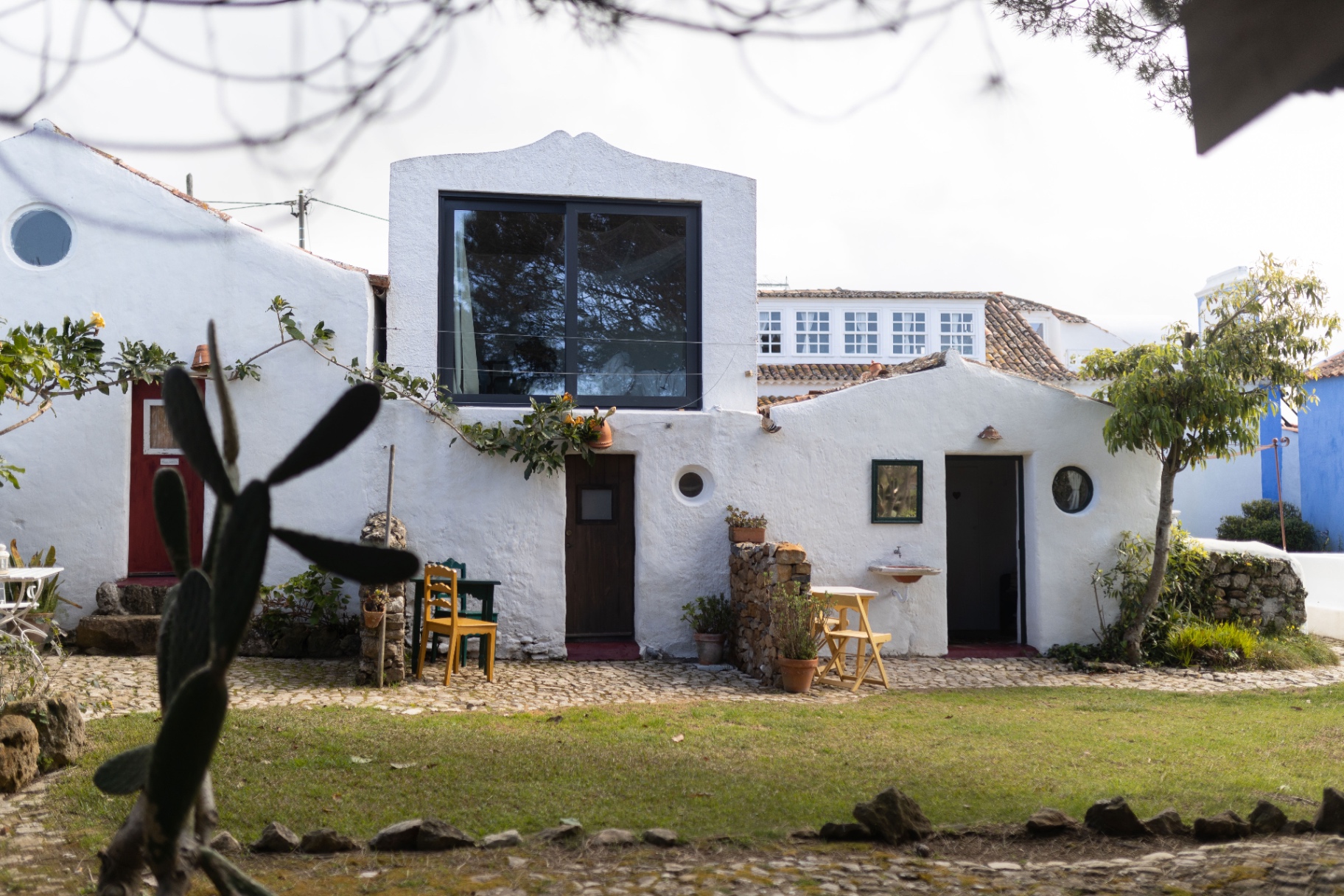 Whitewashed Casa Paco d'Ilhas courtyard with red and green doors