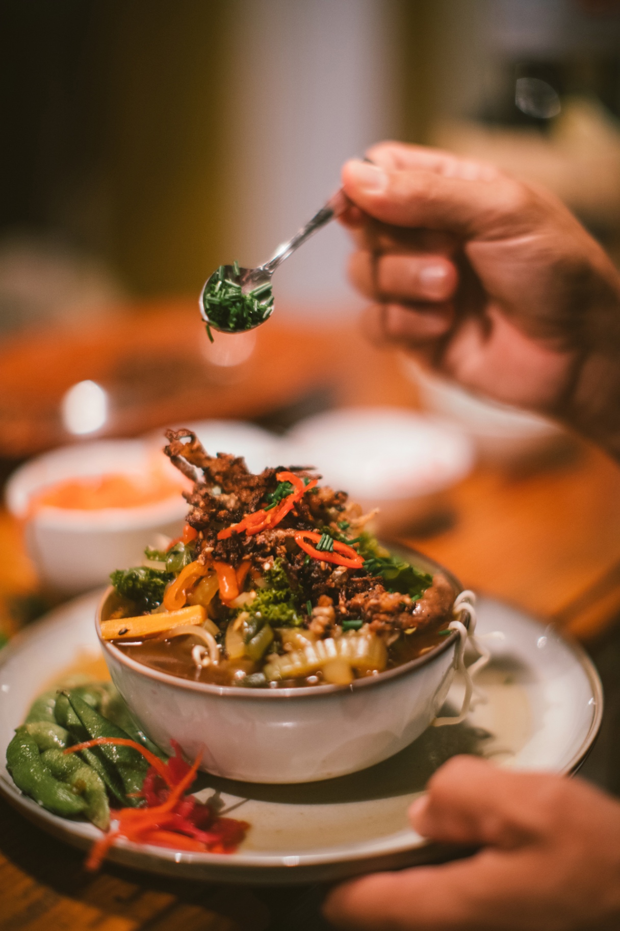 Chef finishing a bowl with fresh herbs