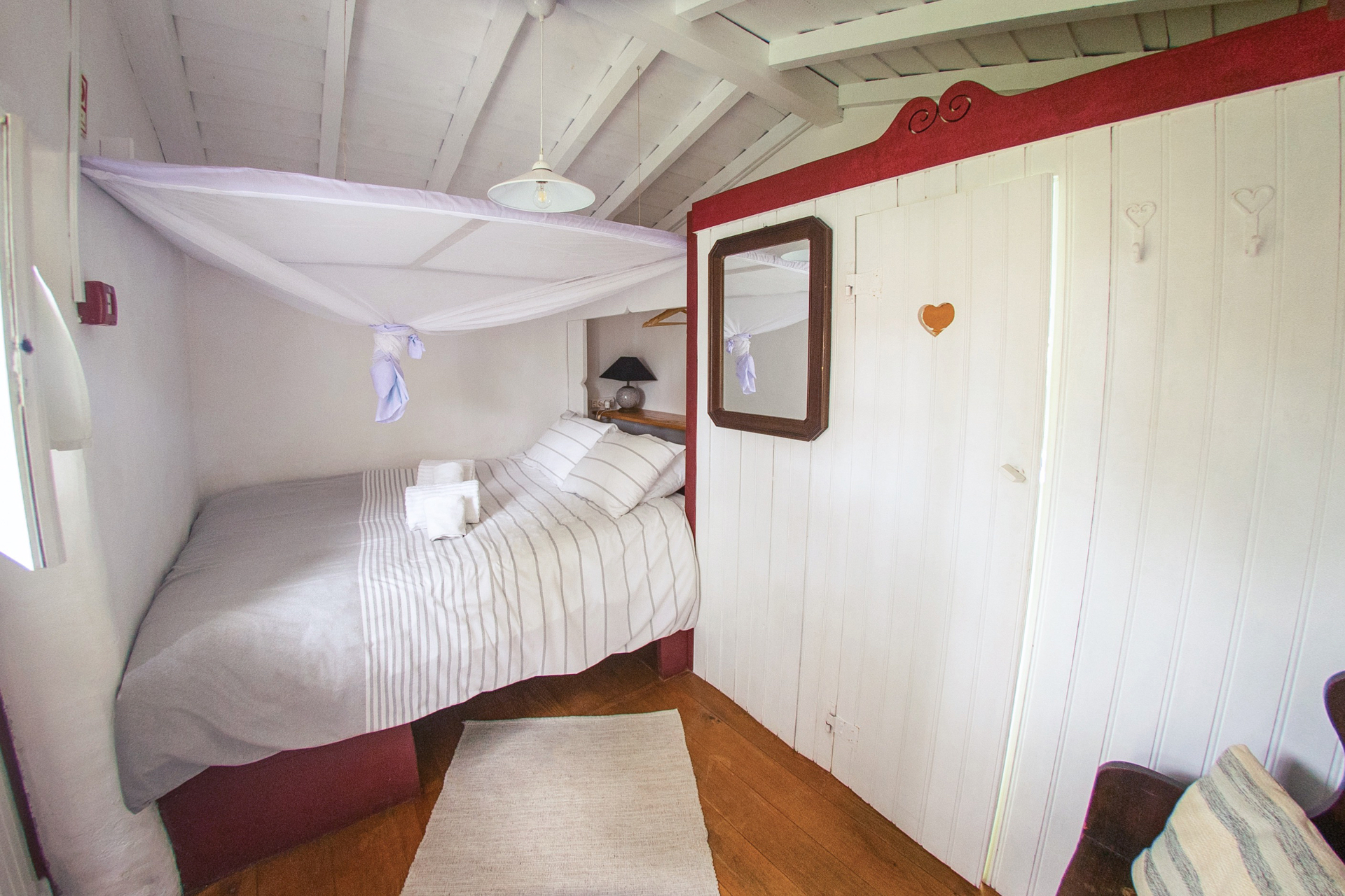 Cozy bedroom with linen canopy over the bed and red trim