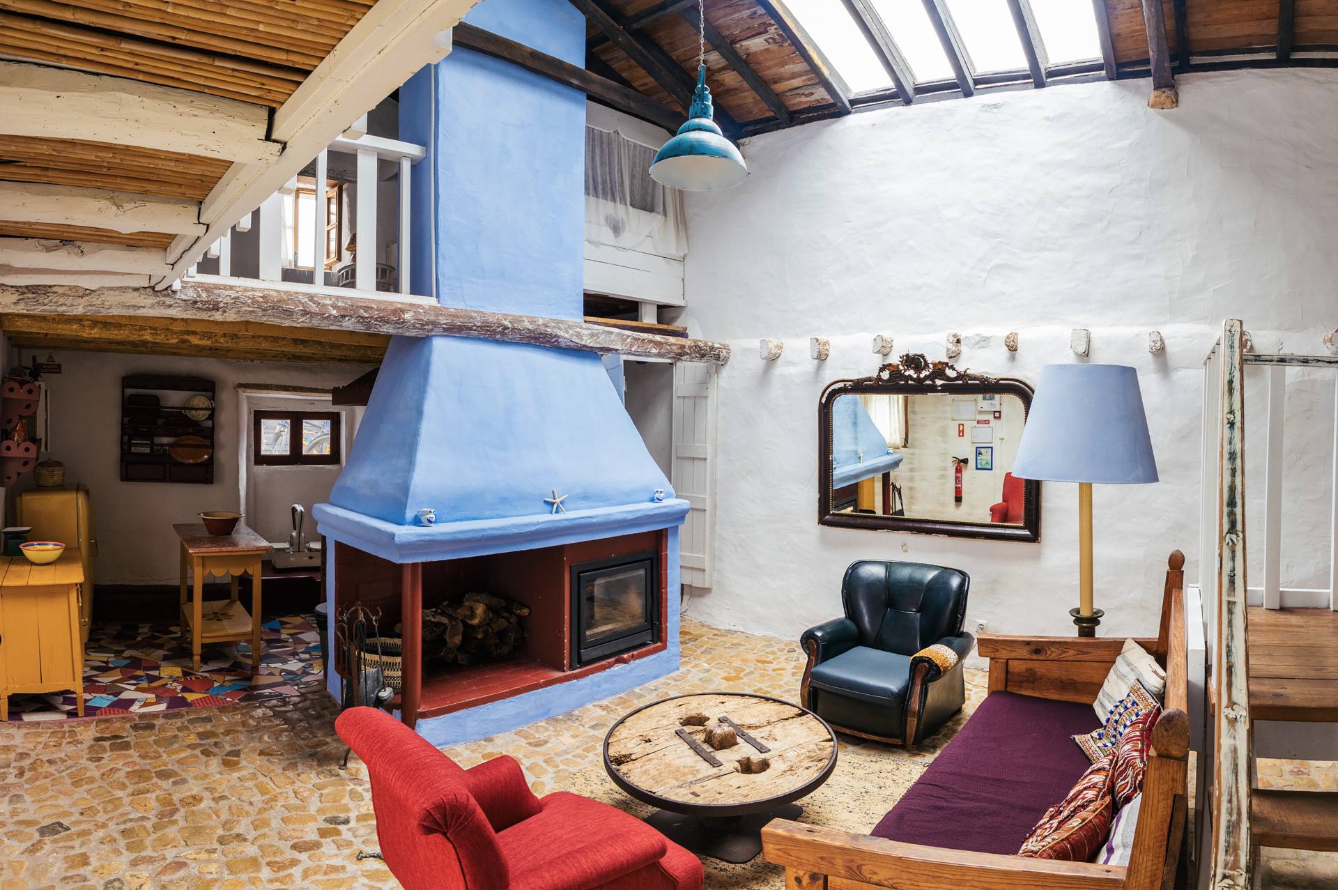 Casa Palheiro living room with tall blue fireplace and skylit beams