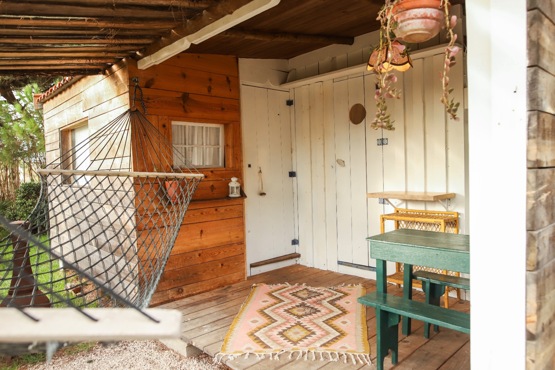 Wooden porch at Casa Jardim with hammock, table, and white plank door