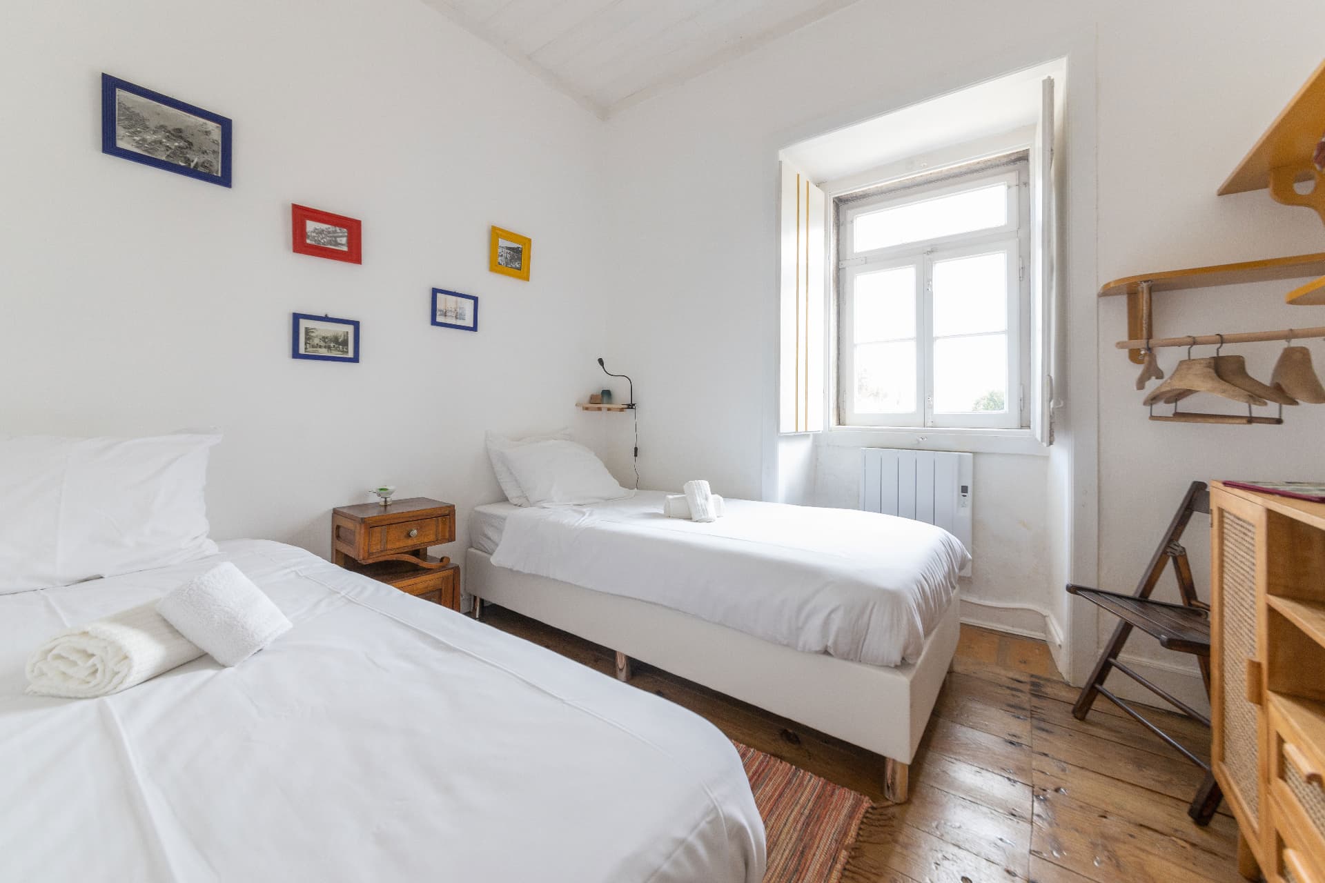 Two twin beds with white linens and framed prints