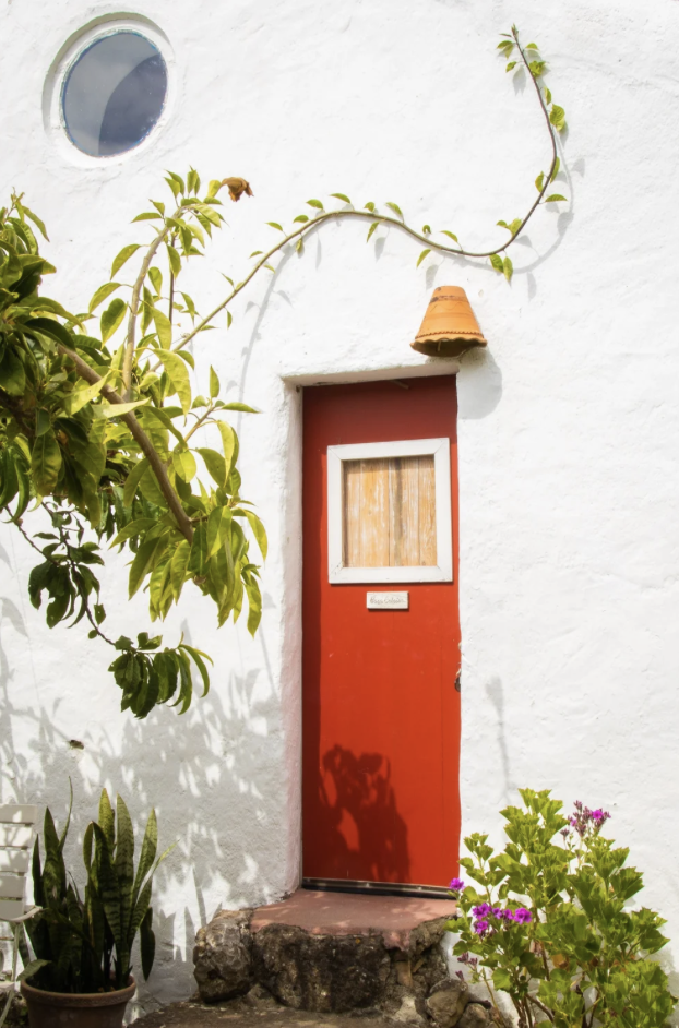 Red door of Casa Paco d'Ilhas framed by bougainvillea