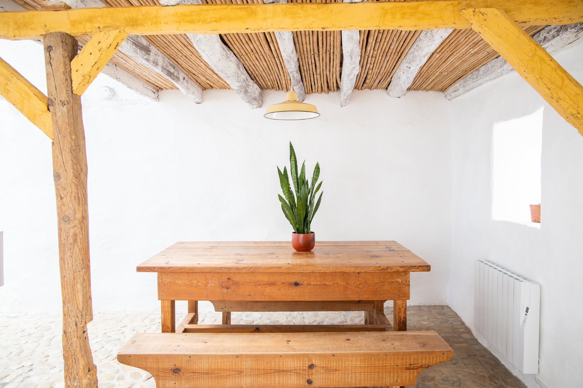 Rustic dining nook with long wooden table and bamboo ceiling